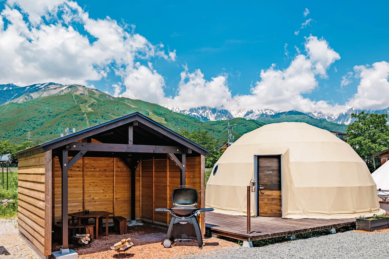 白馬の山並みを背にした、From Pのドーム型の客室とBBQグリル付きのデッキ